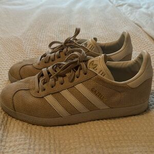 Cream colored Adidas Gazelle with white stripes